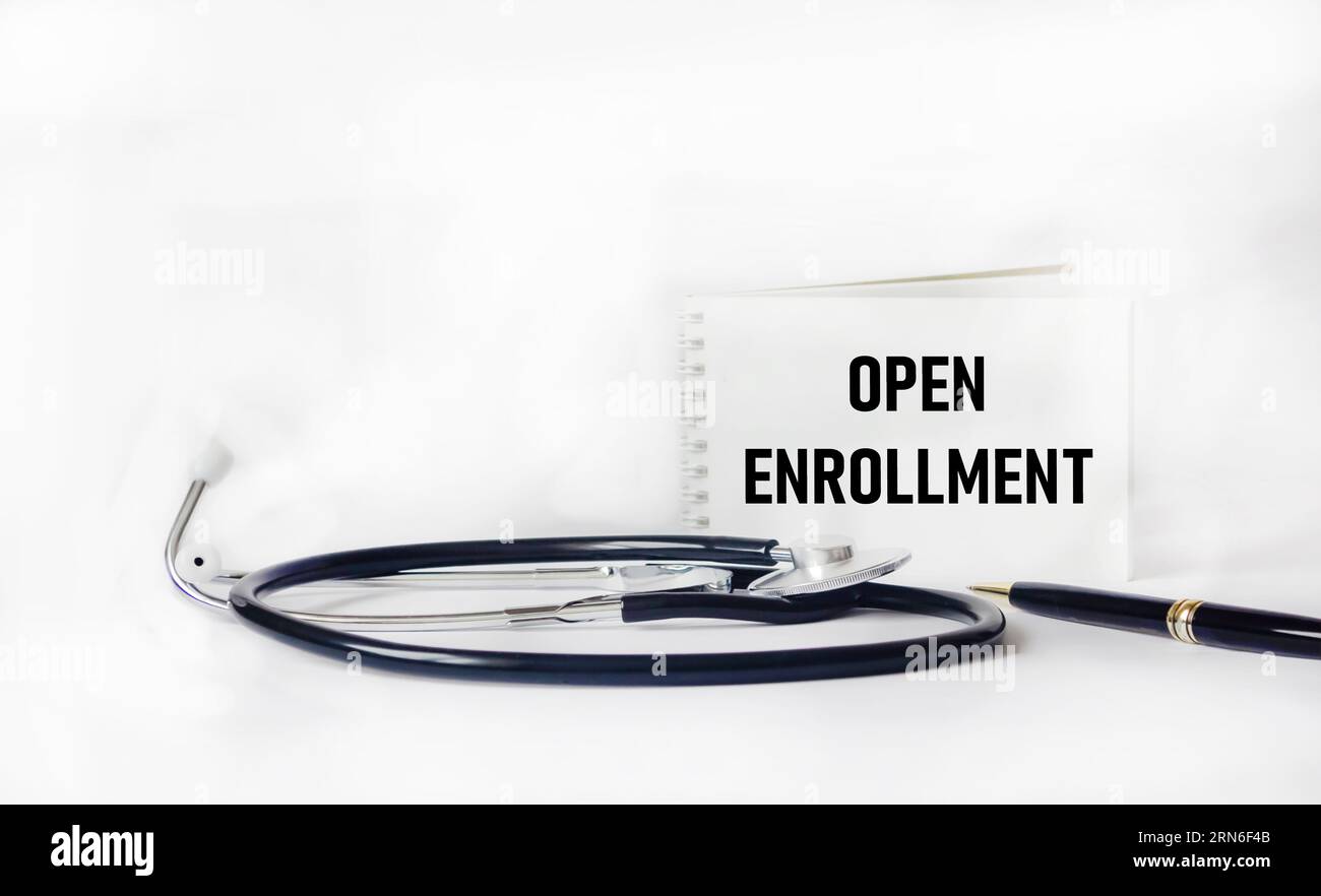 Stethoscope and notepad with text OPEN ENROLLMENT on white background. Medical concept. Stock Photo