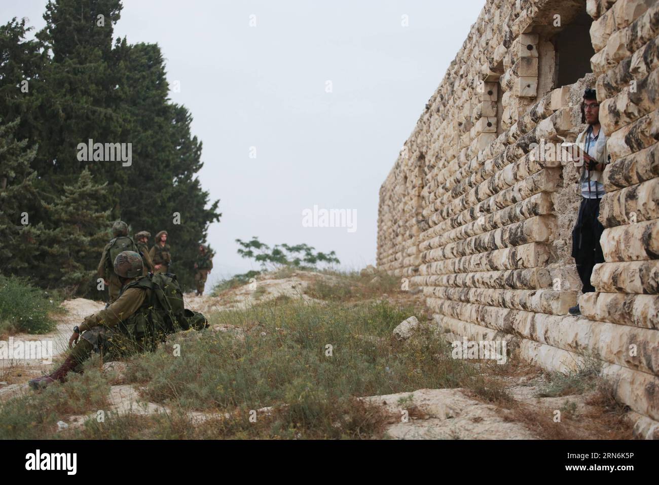 (150730) -- JERUSALEM, July 30, 2015 -- An Israeli Jewish settler prays while Israeli security forces guard in the settlement of the Sa-Nur in the northern West Bank, on July 30, 2015. Israeli security forces on Thursday evacuated about 200 settlers from the site of the former illegal settlement of the Sa-Nur in the northern West Bank, a military spokesperson said in a statement. Since Sa-Nur was evacuated as part of the 2005 Disengagement plan from Gaza, former Sa-Nur residents have made several attempts to rebuild their settlement. /Miri Tzachi) ISRAEL OUT MIDEAST-WEST BANK-ILLEGAL SETTLEMEN Stock Photo