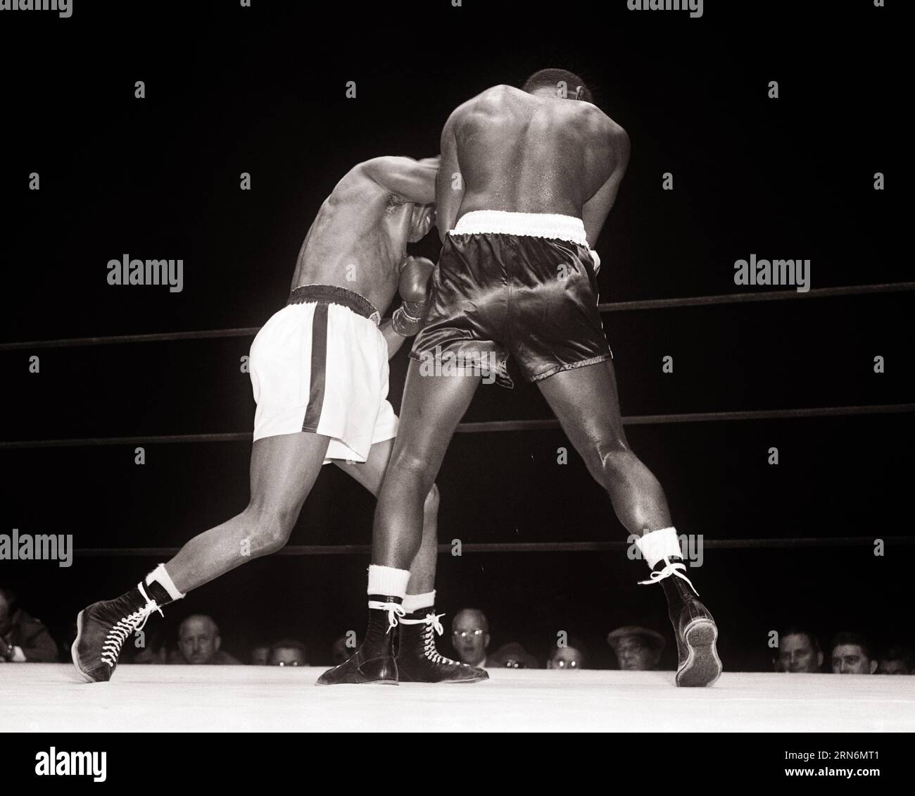 1950s BACK VIEW TWO AFRICAN AMERICAN BOXERS HEAVYWEIGHT BOUT ARCH RIVALS JERSEY JOE WALCOTT LIGHT TRUNKS VS EZZARD CHARLES DARK - p1397 HAR001 HARS OCCUPATIONS FROM BEHIND PUGILIST RIVALS JOE PUGILISM BACK VIEW BOUT CHARLES MID-ADULT MID-ADULT MAN TRUNKS BLACK AND WHITE HAR001 OLD FASHIONED AFRICAN AMERICANS Stock Photo