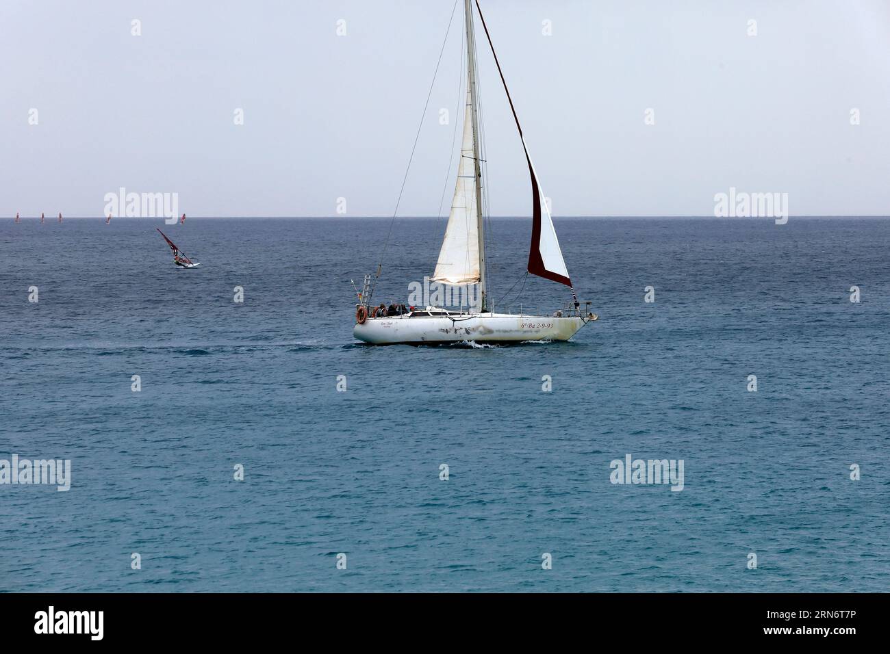 Sailing boat with sail board in the distance and several small