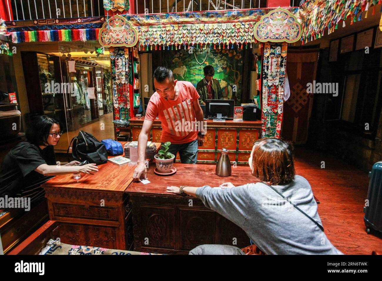 (150807) -- LHASA,  - Lobsang Tashi (C) helps guests check in at one of his traditional Tibetan style hotels in Lhasa, capital of southwest China s Tibet Autonomous Region, Aug. 5, 2015. Born in a mountain village in Shannan Prefecture of Tibet, Lobsang Tashi has long harbored a deep love of the traditional culture of Tibet. In his youth, Lobsang came to the old town of Lhasa and worked as a tour guide. Driven by keen interest in protecting old buildings and culture of Lhasa, Lobsang Tashi got a chance to win a business right to renovate several old buildings into modern decent hotels. In Lobs Stock Photo