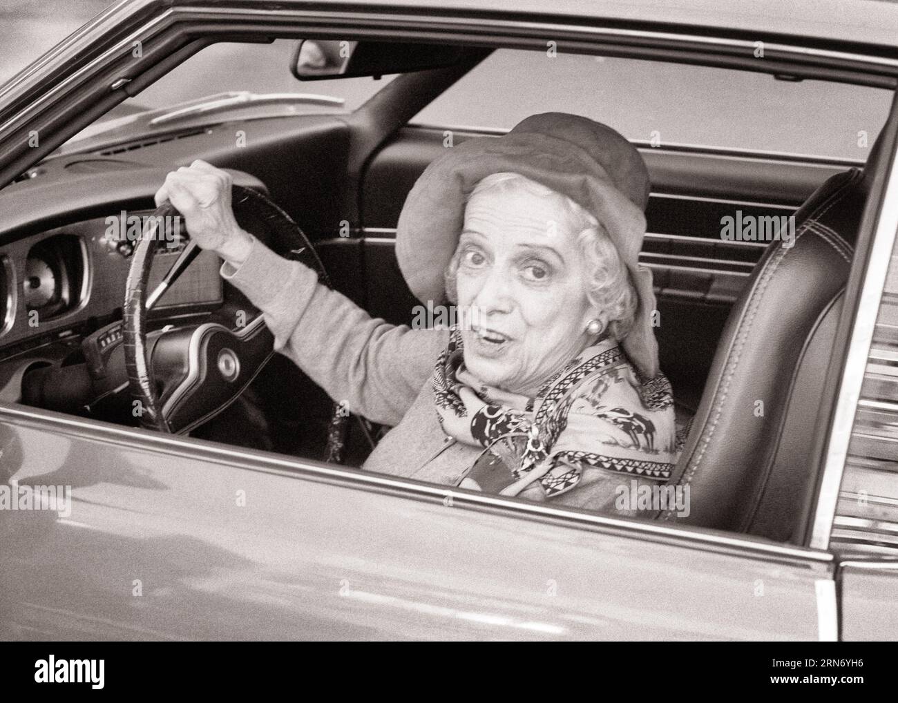 1970s SENIOR WOMAN SITTING IN DRIVER’S SEAT OF CAR LOOKING OUT THE WINDOW AT CAMERA - m9622 HAR001 HARS COMMUNICATION VEHICLE SAFETY FASHIONABLE LIFESTYLE ELDER FEMALES COPY SPACE LADIES PERSONS INSPIRATION AUTOMOBILE CHARACTER DRIVERS CONFIDENCE TRANSPORTATION SENIOR ADULT B&W WIDE EYE CONTACT SENIOR WOMAN BUG-EYED OLD AGE OLDSTERS HEAD AND SHOULDERS HIGH ANGLE OLDSTER ADVENTURE STYLES AUTOS PRIDE ELDERS AUTOMOBILES STYLISH VEHICLES DRIVER'S WIDE-EYED ELDERLY WOMAN FASHIONS STARTLED BLACK AND WHITE CAUCASIAN ETHNICITY HAR001 OLD FASHIONED Stock Photo