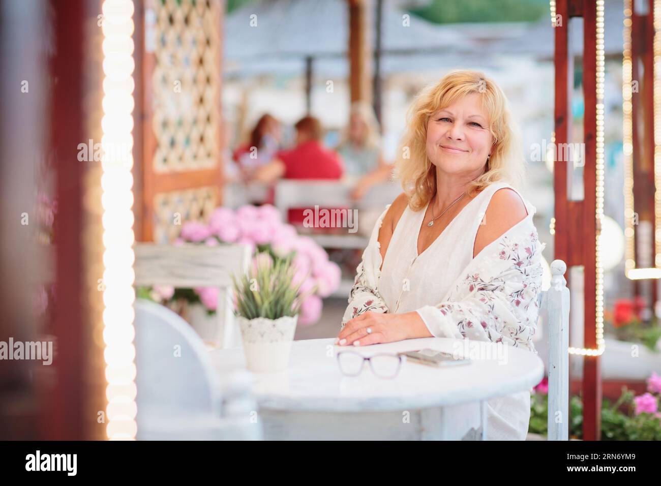 Portrait of woman sitting on the terrace of a beach cafe Stock Photo ...