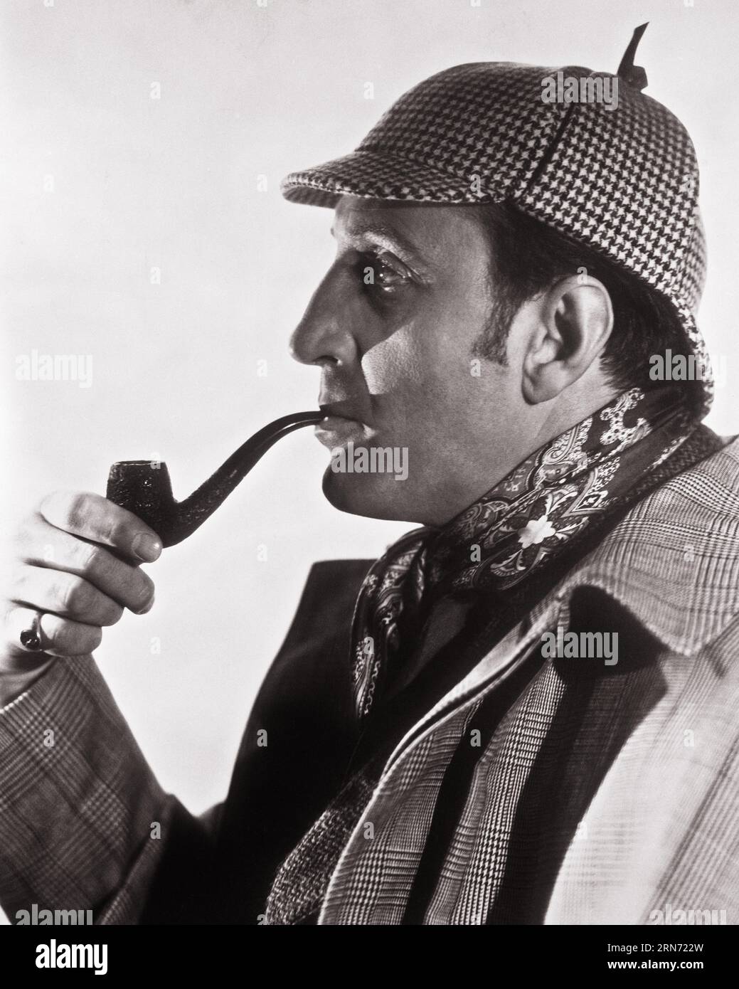 1930s PORTRAIT PROFILE OF ACTOR BASIL RATHBONE AS SHERLOCK HOLMES WITH THE STEREOTYPICAL PIPE AND DEERSTALKER HAT - q73306 CPC001 HARS COURAGE AND EXCITEMENT PRIDE AUTHORITY DETECTIVE ENTERTAINER INVESTIGATE OCCUPATIONS BASIL ACTORS STYLISH DEERSTALKER CONSULTING DETECTIVE MOTION PICTURE MOTION PICTURES PUBLICITY STILL SERIAL BASIL RATHBONE DEDUCTION ENTERTAINERS FICTIONAL MOVIE STILL OBSERVATION PERFORMERS RATHBONE SERIES BLACK AND WHITE CAUCASIAN ETHNICITY OLD FASHIONED Stock Photo