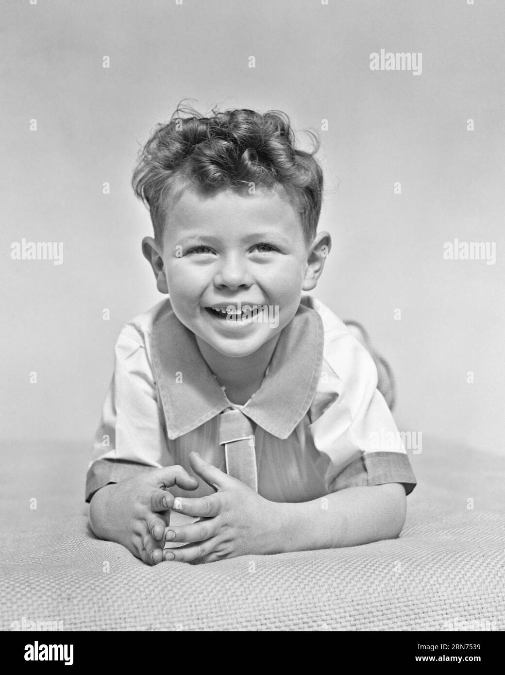 1940s CUTE LITTLE BOY WITH CURLY HAIR SMILING AND LOOKING AT THE CAMERA - j9342 HAR001 HARS CHEERFUL AND EXCITEMENT CURLY SMILES JOYFUL NECK TIE BABY BOY ETON COLLAR PLEASANT AGREEABLE CHARMING GROWTH JUVENILES LOVABLE PLEASING ADORABLE APPEALING BLACK AND WHITE CAUCASIAN ETHNICITY HAR001 OLD FASHIONED Stock Photo