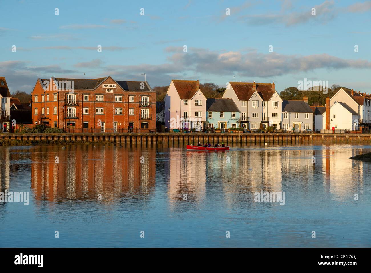 Late on a December afternoon, a riverside housing development of new, old and refurbished property almost glows in setting sun light under a blue sky. Stock Photo