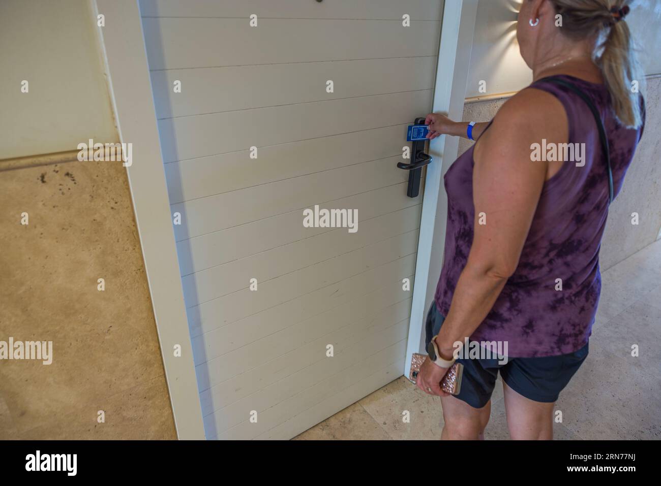Closeup view of woman opening electric lock of front door with key