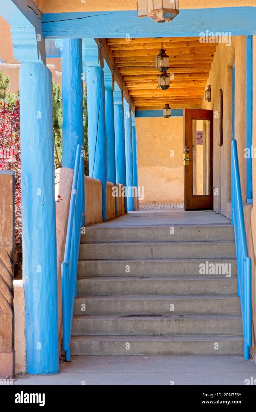 Stairwell to landing under wood viga roof beams, lanterns and blue wood columns in shopping district of Taos New Mexico Stock Photo