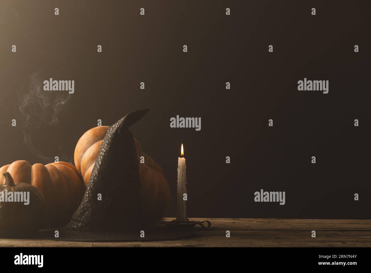 Pumpkins and witch hat and burning candle with copy space on grey background Stock Photo