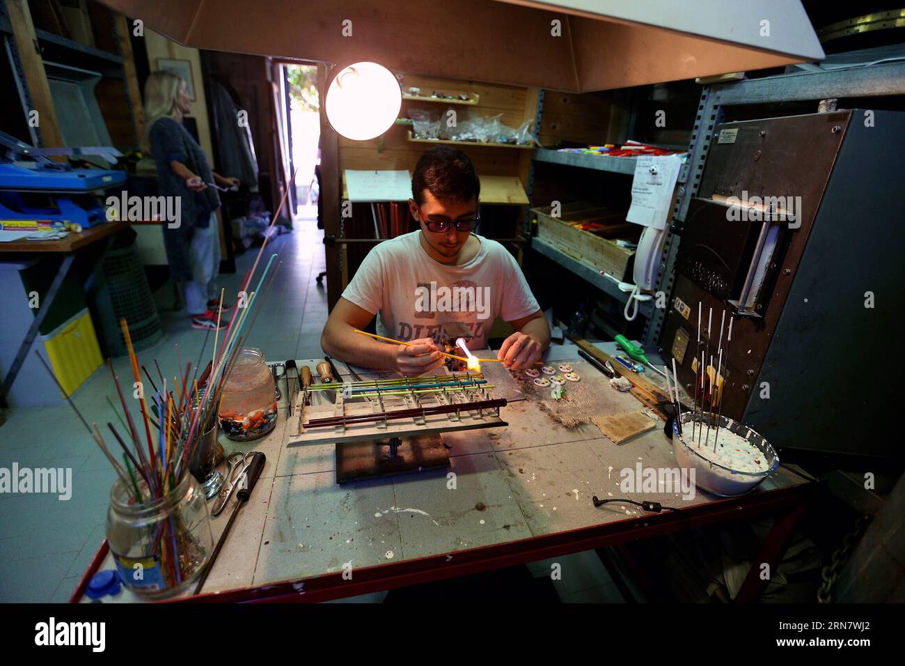 (150922) -- MURANO, Sept. 22, 2015 -- Matteo makes a piece of glass jewelry with a desk oven at his studio LAV in Murano of Venice, Italy, on Sept. 9, 2015. Murano is famous for its glass-making techniques. In the late 13th century, all the glassmakers in Venice were forced to move to Murano due to the danger of fire. Then, the island became famous for glass beads, mirrors, goblets and chandeliers. Nowadays, Murano still keeps many factories using traditional techniques just as people did centuries ago. Murano s glass business now faces threaten as imported glass products with lower price. ) I Stock Photo