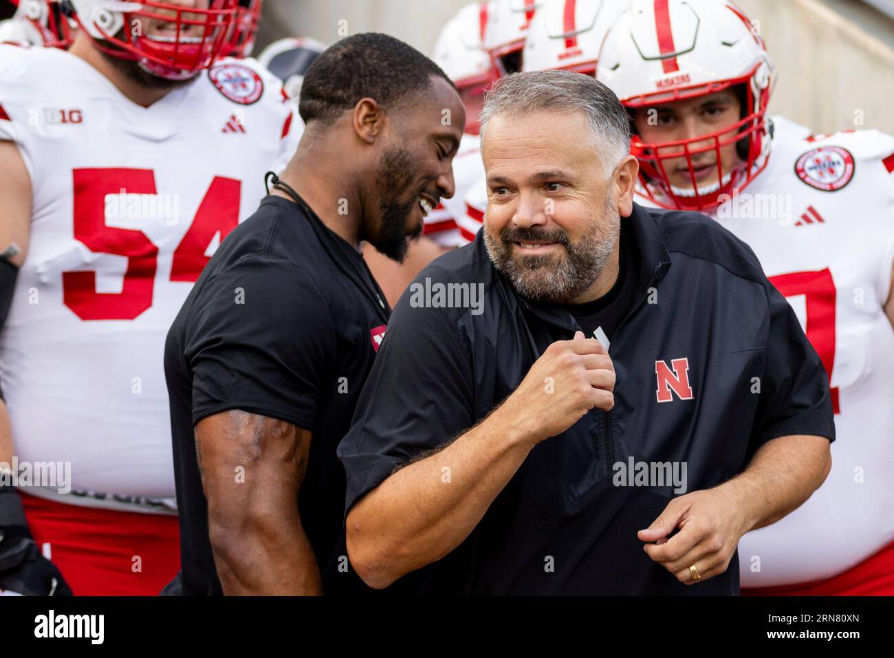 Nebraska head coach Matt Rhule sneaks through players warming up for an
