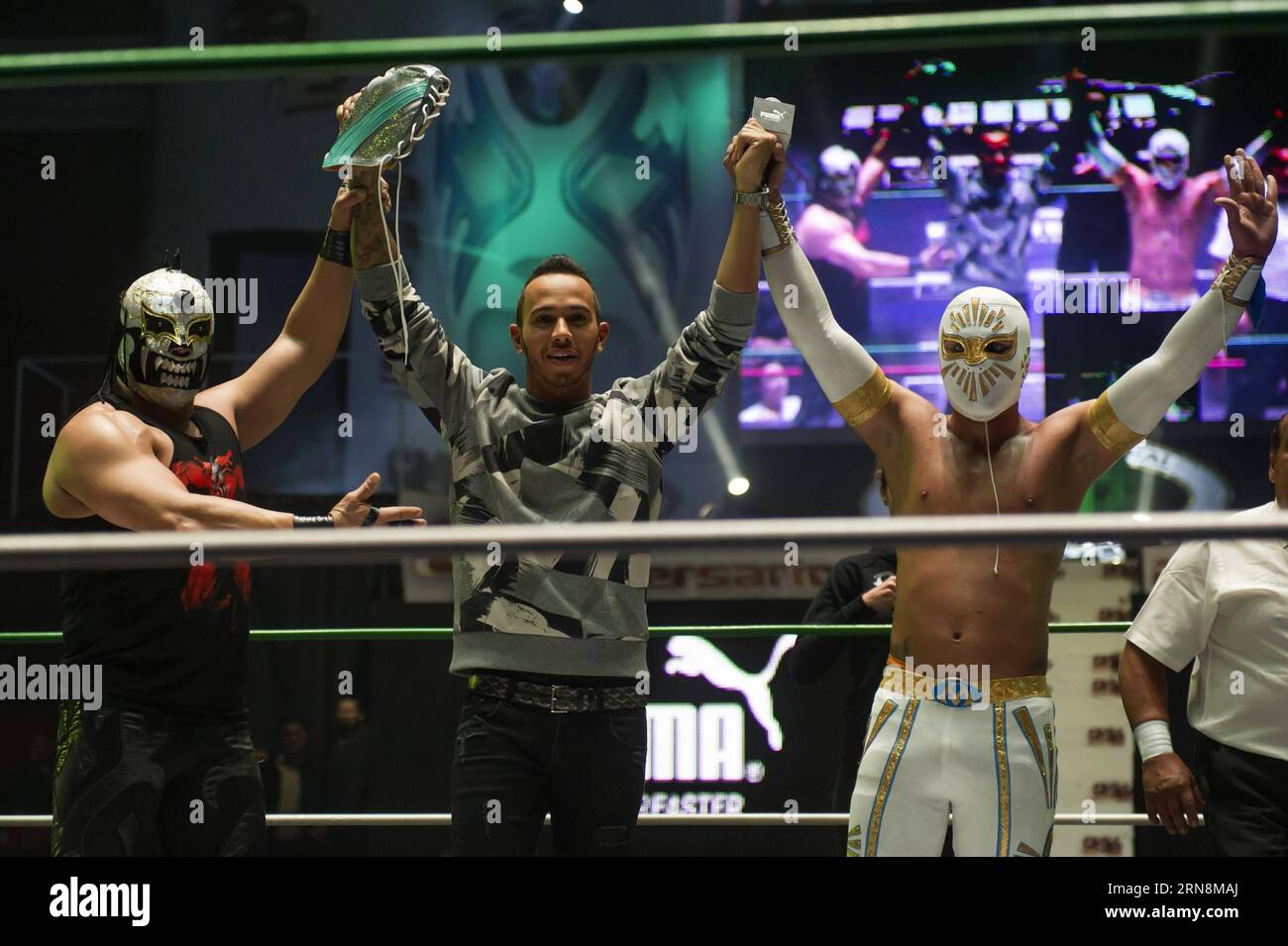 (151029) -- MEXICO CITY,  - British driver Lewis Hamilton (C) of Mercedes team, takes part during a wrestling exhibition with Mistico (R) wrestler, during his visit to Arena Mexico, prior to the F1 Mexican Grand Prix, in Mexico City, capital of Mexico, on Oct. 28, 2015. According to local press, Lewis Hamilton visited on Wednesday the Arena Mexico, where he watched a wrestling exhibition and played a match of table football at the ring with Mexican soccer player Oribe Peralta. The F1 Mexican Grand Prix will be held from Oct. 30 to Nov. 1, in Mexico City. ) (SP)MEXICO-MEXICO CITY-AUTOMOBILE-F1 Stock Photo