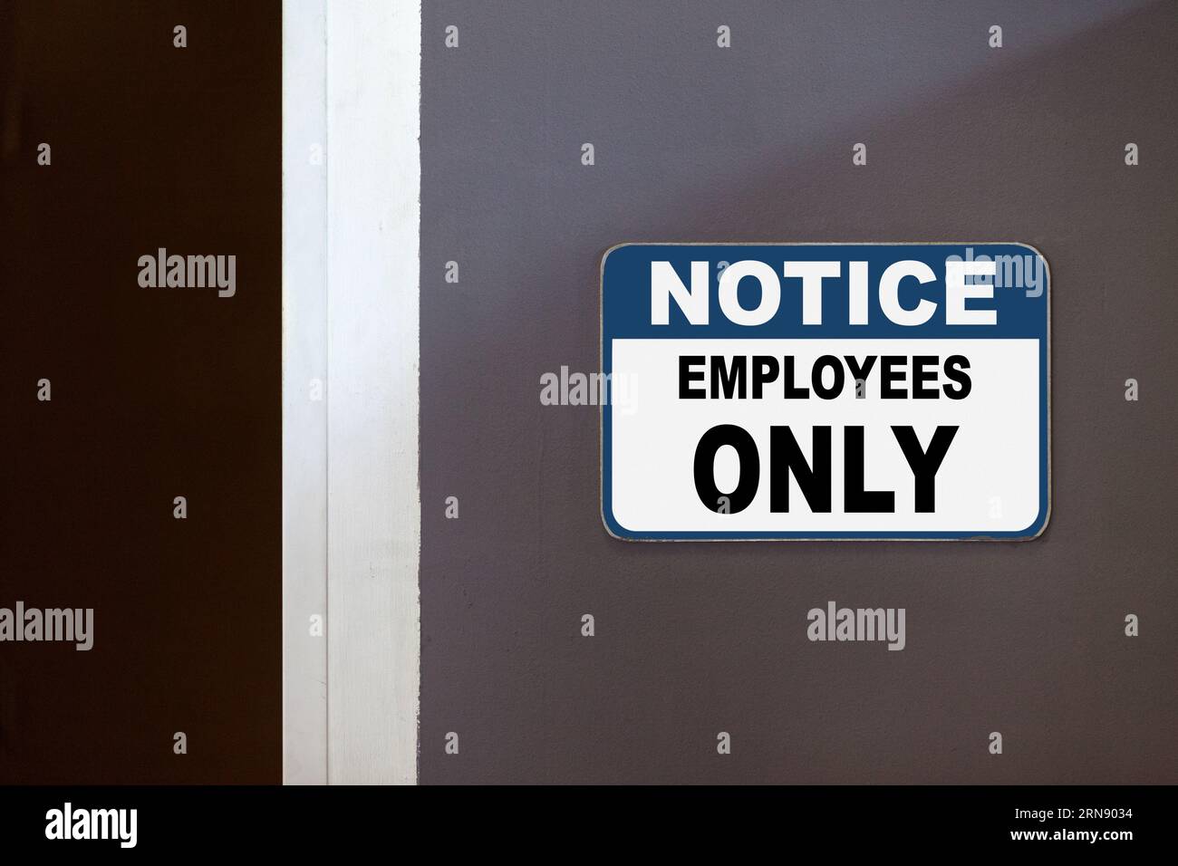 Blue and white notice sign on the side of an open door stating : Notice, employees only. Stock Photo