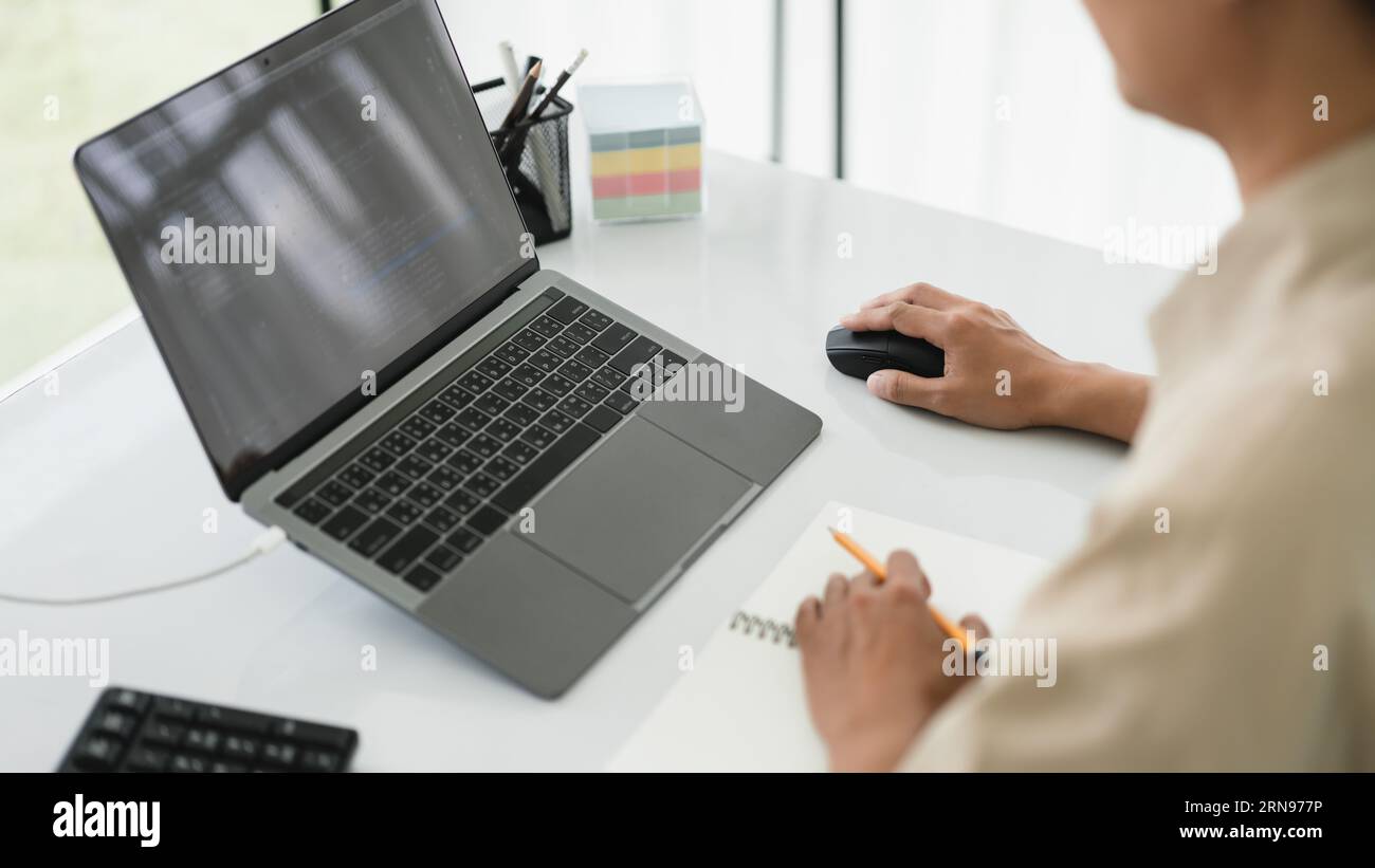 Developer programmer use mouse and checking code on laptop while programming to developing website. Stock Photo