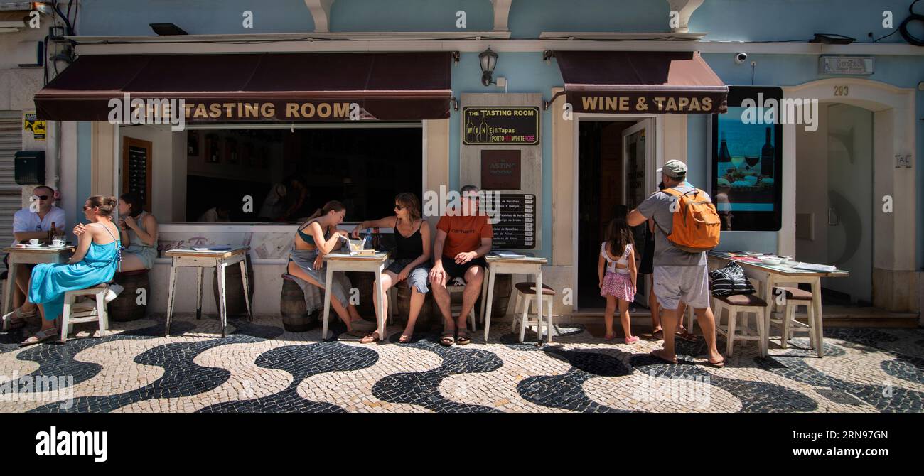 Wine and Tapas bar on Rue Fredrico Arouca Street, Cascais, Portugal.  Arouca Street a pedestrian street in Cascais at the center of the old part of the city.  The cobble stone street lined with shops, restaurants and wine bars on a summer Sunday afternoon. Stock Photo