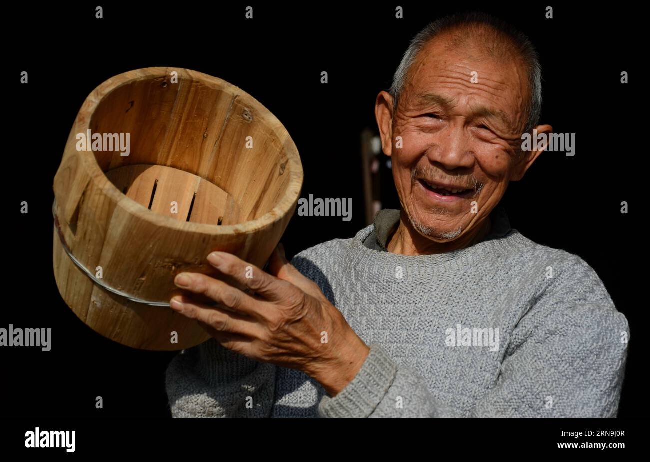 (151208) -- QIANGJIANG(HUBEI), Dec. 7, 2015 -- Mao Dehui shows his wooden cauldron at home in Qianjiang, central China s Hubei Provicne, on Dec. 7, 2015. Mao Dehui, 81, has been working on wooden cauldron since he began to learn at 14 and began to make a living with cauldron making afterwards. With this handicraft, he attended the carpenter organization during China s planned economy time and worked at home after China s economic reform. As China is industrializing, the market of hand-made wooden cauldron, used to be a household necessity to make steamed rice, is narrowing rapidly and vinishin Stock Photo