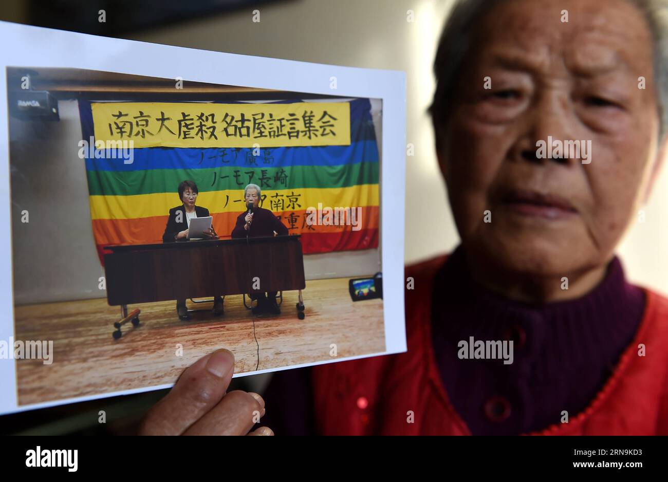 Ai Yiying, 87, survivor of the atrocious Nanjing Massacre, shows her photo at home in Nanjing, capital of east China s Jiangsu Province, on Dec. 3, 2015. Ai Yiying survived in the Nanjing Massacre when she was 9 years old. She witnessed in a hideout that her father Ai Renyin, her uncles Ai Renbing and Ai Renlin, her cousin Ai Yisheng were forced away and killed by Japanese army. Some survivors of the Nanjing Massacre held family memorial rites for their lost relatives at the Memorial Hall of the Victims in the Nanjing Massacre by Japanese Invaders, ahead of the national memorial day for the at Stock Photo