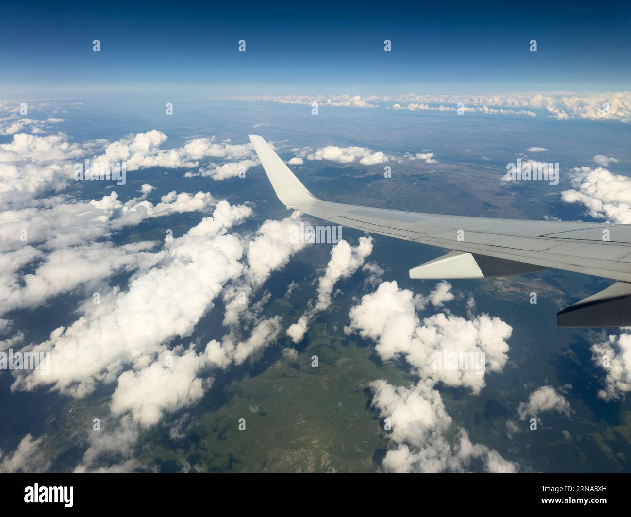 White wing from airplane window with mountain range below on sunny day ...