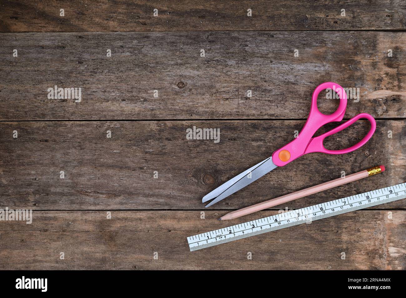 A flat, top view of an Arts and Crafts background with a pair of scissors, pencil and ruler in a rustic wooden setting with copy space Stock Photo