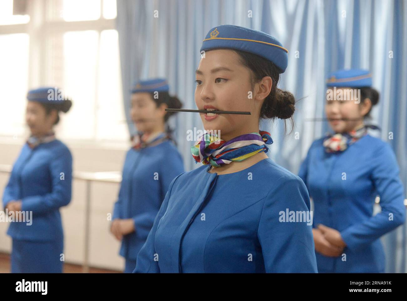 Flugbegleiter-Schule in China CHONGQING, Jan. 13, 2016 -- Students hold chopsticks in the mouths to keep smile in training at Bishan Vocational Education Center in Chongqing, southwest China, Jan. 13, 2016. These students were trained to be stewardesses of the high-speed train. ) (ry) CHINA-CHONGQING-STEWARDESS TRAINING (CN) XiexJie PUBLICATIONxNOTxINxCHN   Flight attendants School in China Chongqing Jan 13 2016 Students Hold Chopsticks in The mouths to keep Smile in Training AT Bishan Vocational Education Center in Chongqing Southwest China Jan 13 2016 Thesis Students Were trained to Be stewa Stock Photo