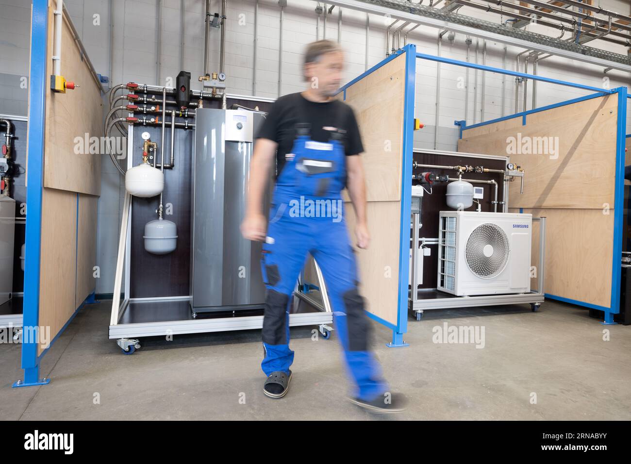 31 August 2023, Brandenburg, Groß Kreutz: A man walks along in front of heat pumps in the 'Heat Pump Laboratory' of the Potsdam Chamber of Crafts at the Handwerk Education and Innovation Campus (BIH). Photo: Sebastian Christoph Gollnow/dpa Stock Photo