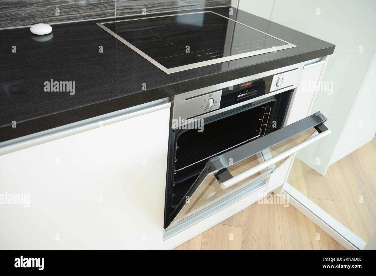 Modern kitchen with open door electric oven and induction cooktop