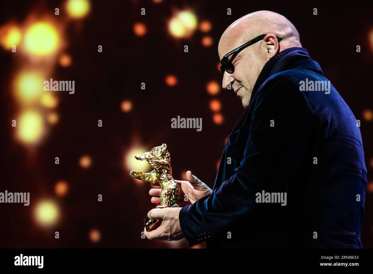 Italian director Gianfranco Rosi holds the trophy of Golden Bear for Best Film for the film Fire at Sea during the awards ceremony of the 66th Berlinale International Film Festival in Berlin, Germany, Feb. 20, 2016. The Italian documentary film Fire at Sea won the Golden Bear, the top jury prize awarded to the best film, in the 66th Berlin International Film Festival on Saturday. ) GERMANY-BERLIN-BERLINALE INTERNATIONAL FILM FESTIVAL-AWARDS CEREMONY-GOLD BEAR-GIANFRANCO ROSI ZhangxFan PUBLICATIONxNOTxINxCHN   Italian Director Gian Franco Rosi holds The Trophy of Golden Bear for Best Film for T Stock Photo