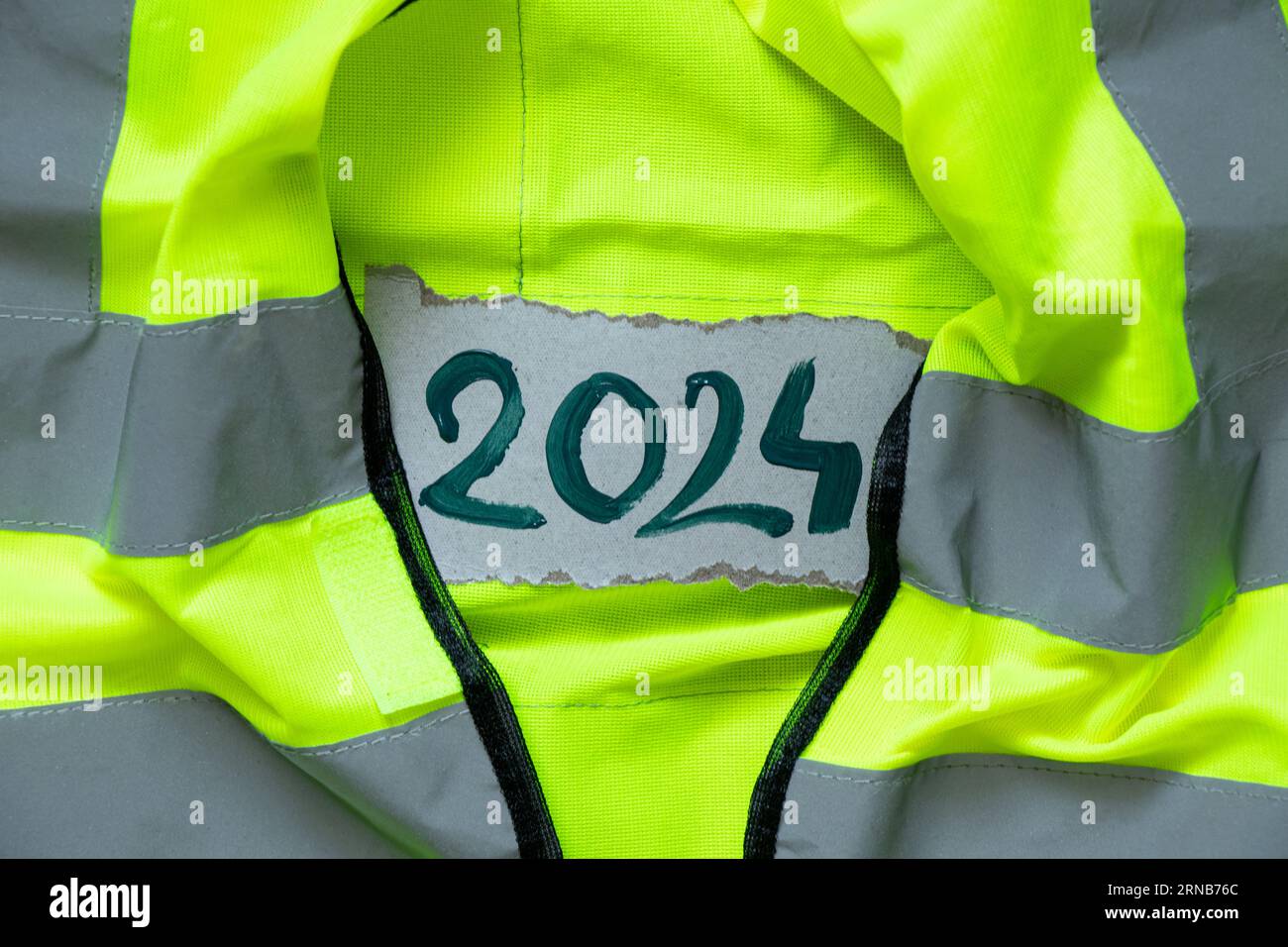 2024 written in green paint lies on a reflective vest, Happy New Year 2024, banner and background, special clothing and work Stock Photo