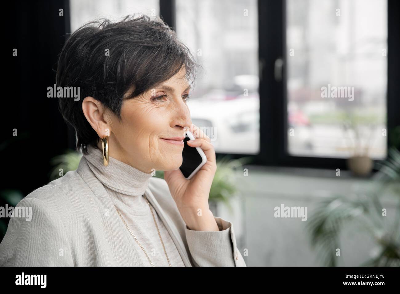 happy and stylish middle aged businesswoman calling on mobile phone in modern work environment Stock Photo