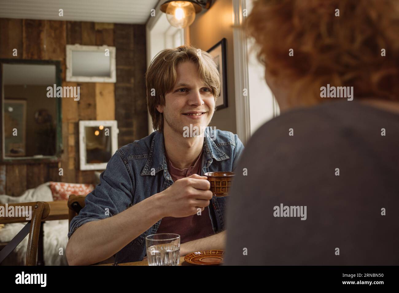 Man sitting at table with red haired woman and drinking coffee Stock Photo