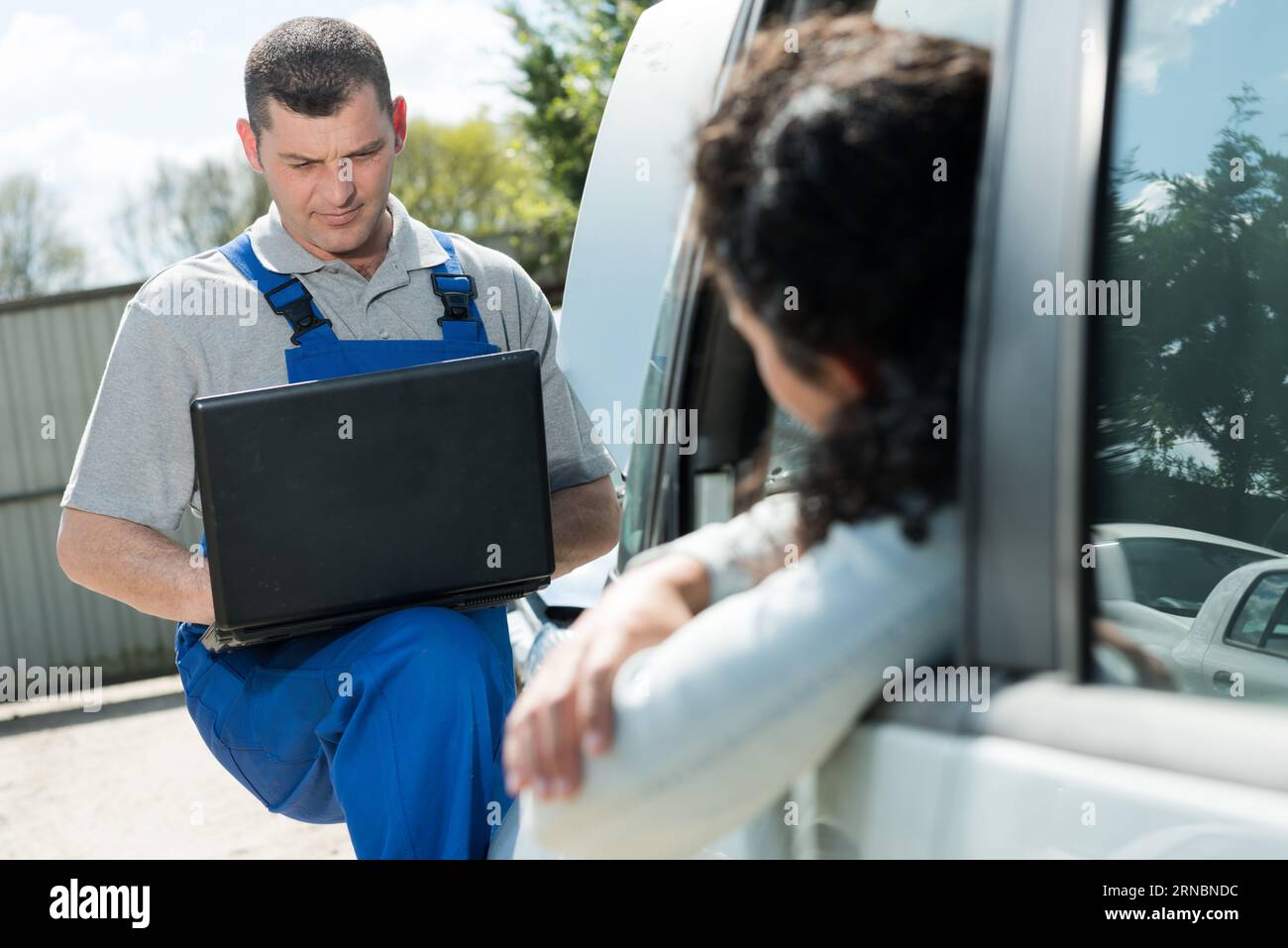 male mechanic using laptop for examining car engine Stock Photo