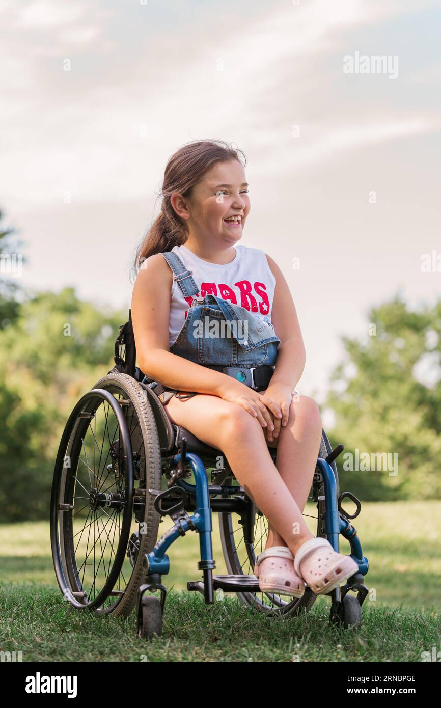 A young girl in a wheelchair laughing while at the park Stock Photo - Alamy