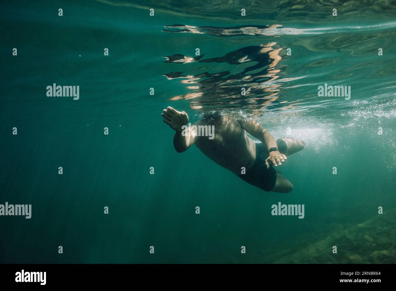 A young hispanic male swims through cold, blue water. Stock Photo