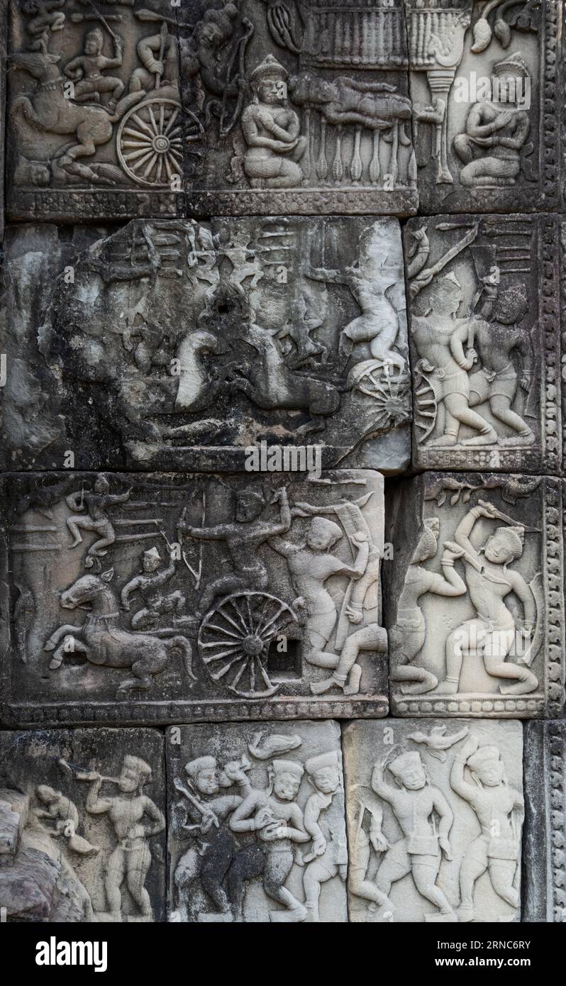 A vertical of stone carvings of Khmer warriors in chariots and war horses in Angkor Wat temple Stock Photo