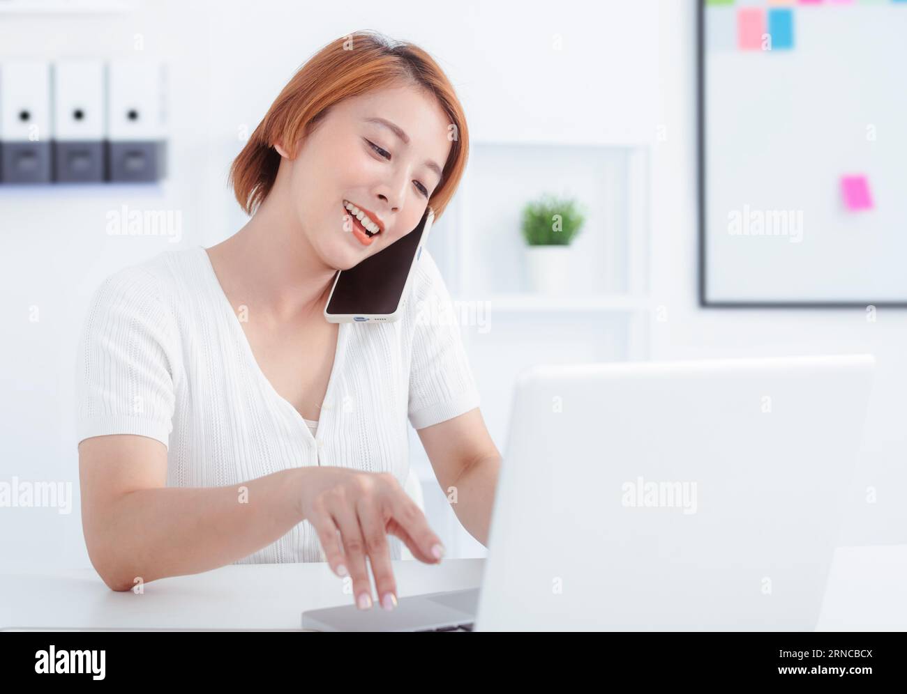 Happy woman using mobile phone and laptops for work. Stock Photo
