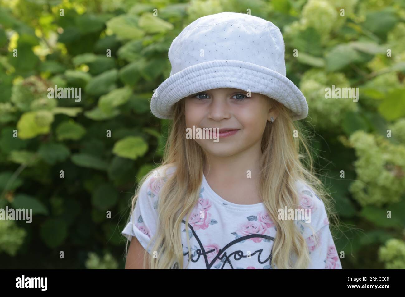 Candid outdoor portrait of happy little girl with bucket hat Stock