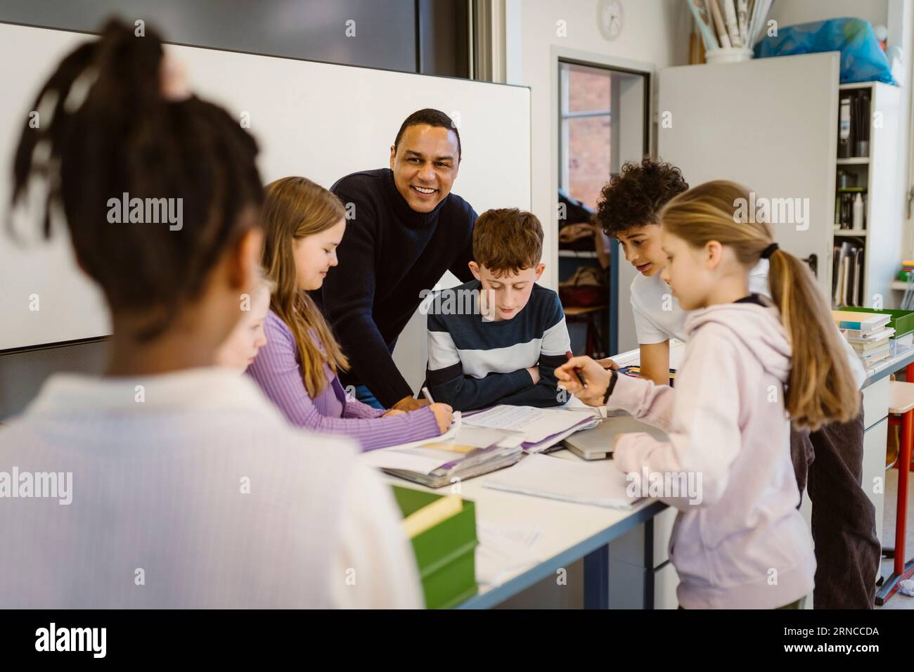 Happy teacher with multiracial students at desk in classroom Stock ...