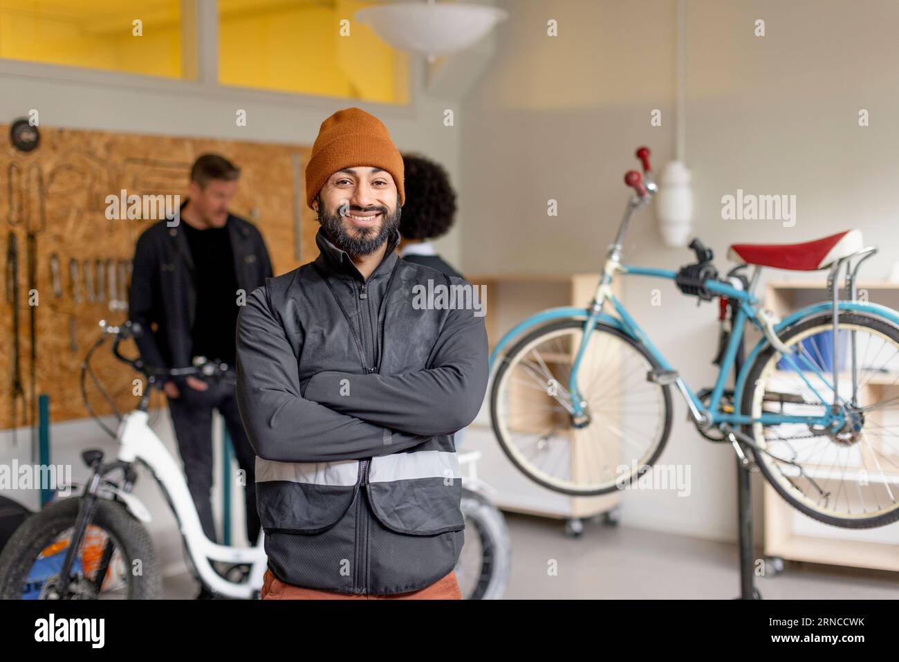 Portrait of happy male worker with arms crossed during cycle repairing workshop at recycling center Stock Photo