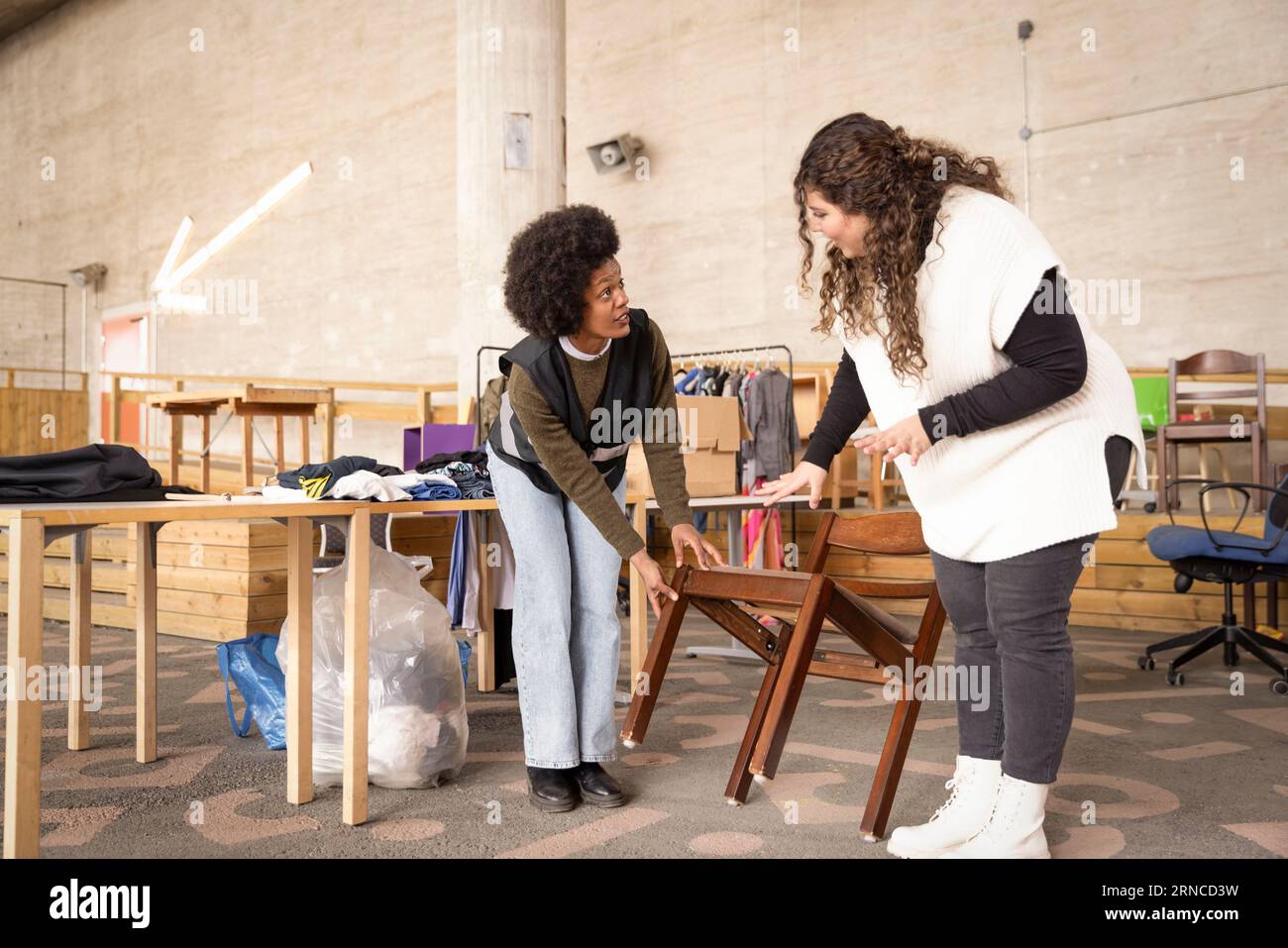 Female workers discussing over wooden chair at recycling center Stock Photo