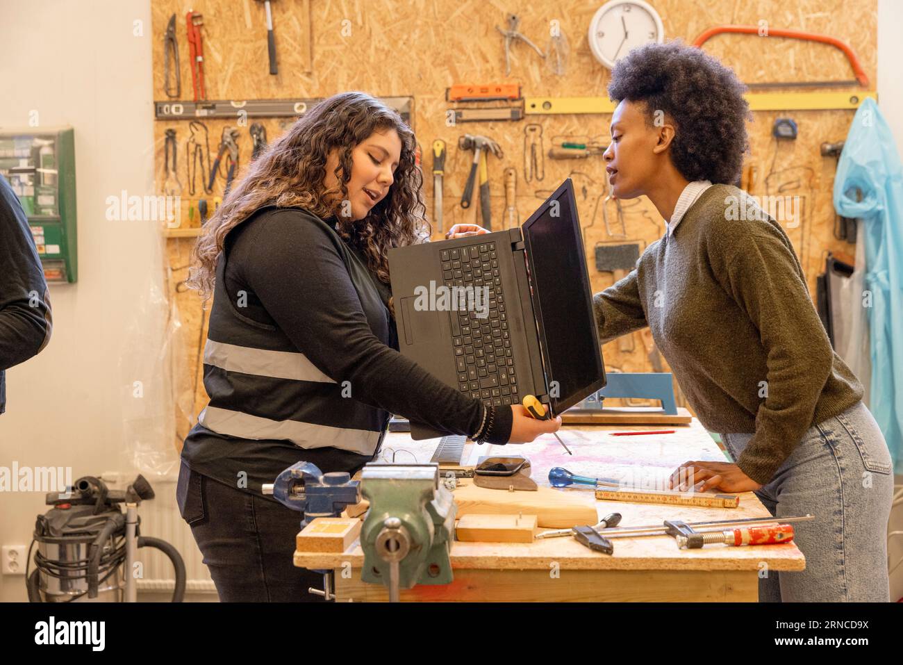 Side view of female customer discussing over laptop with worker at recycling center Stock Photo