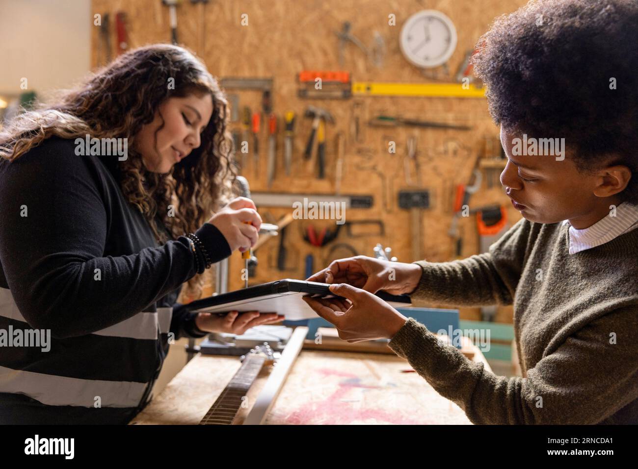 Woman helping technician repairing laptop using tool at recycling center Stock Photo