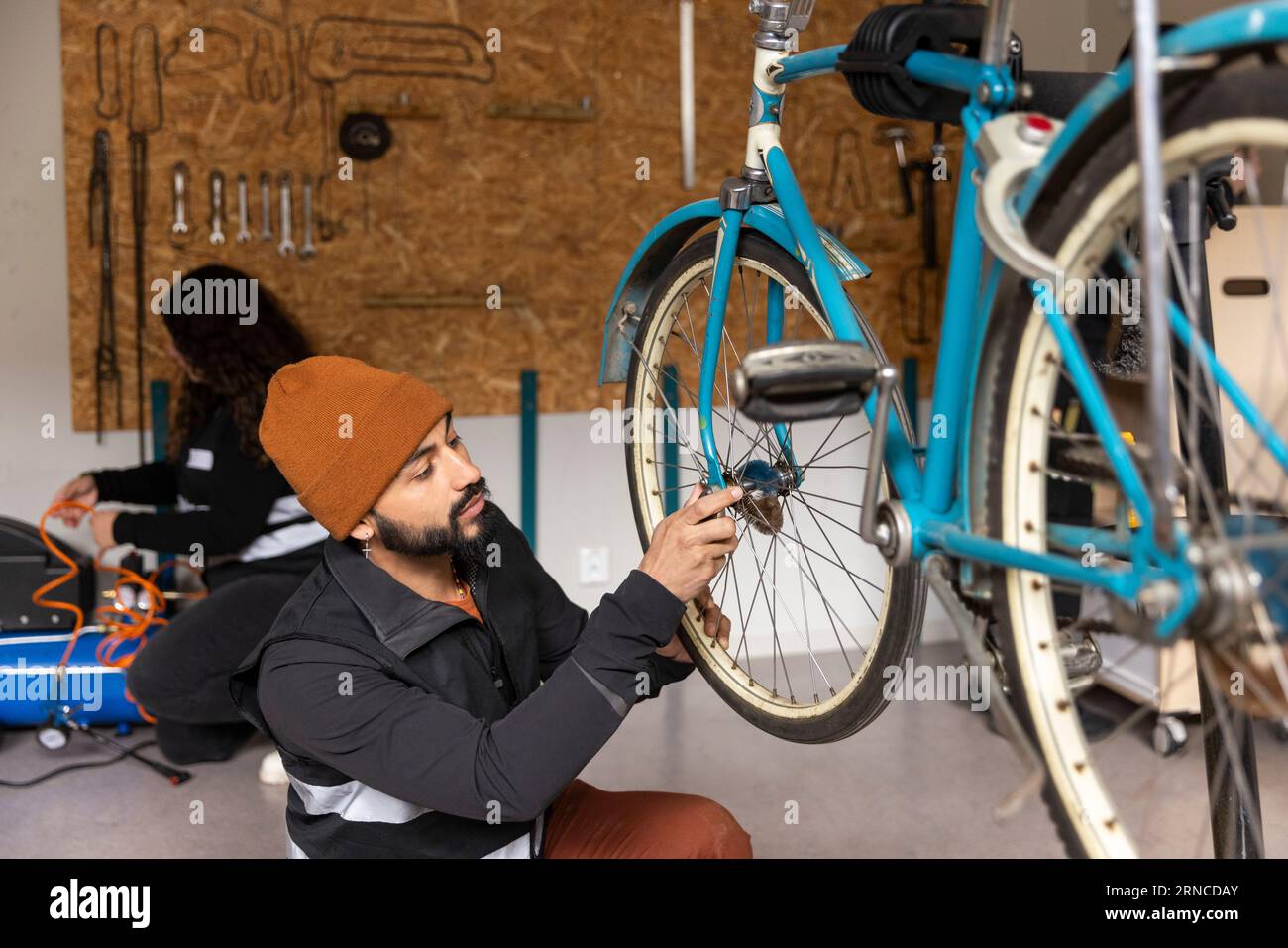 Male technician repairing bicycle wheel in workshop at recycling center Stock Photo