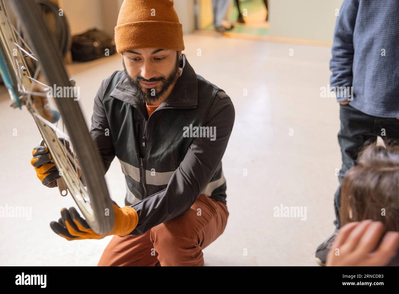 Male technician examining bicycle wheel at recycling center Stock Photo