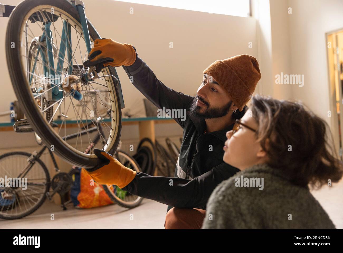 Male technician tightening bicycle wheel by boy at recycling center Stock Photo