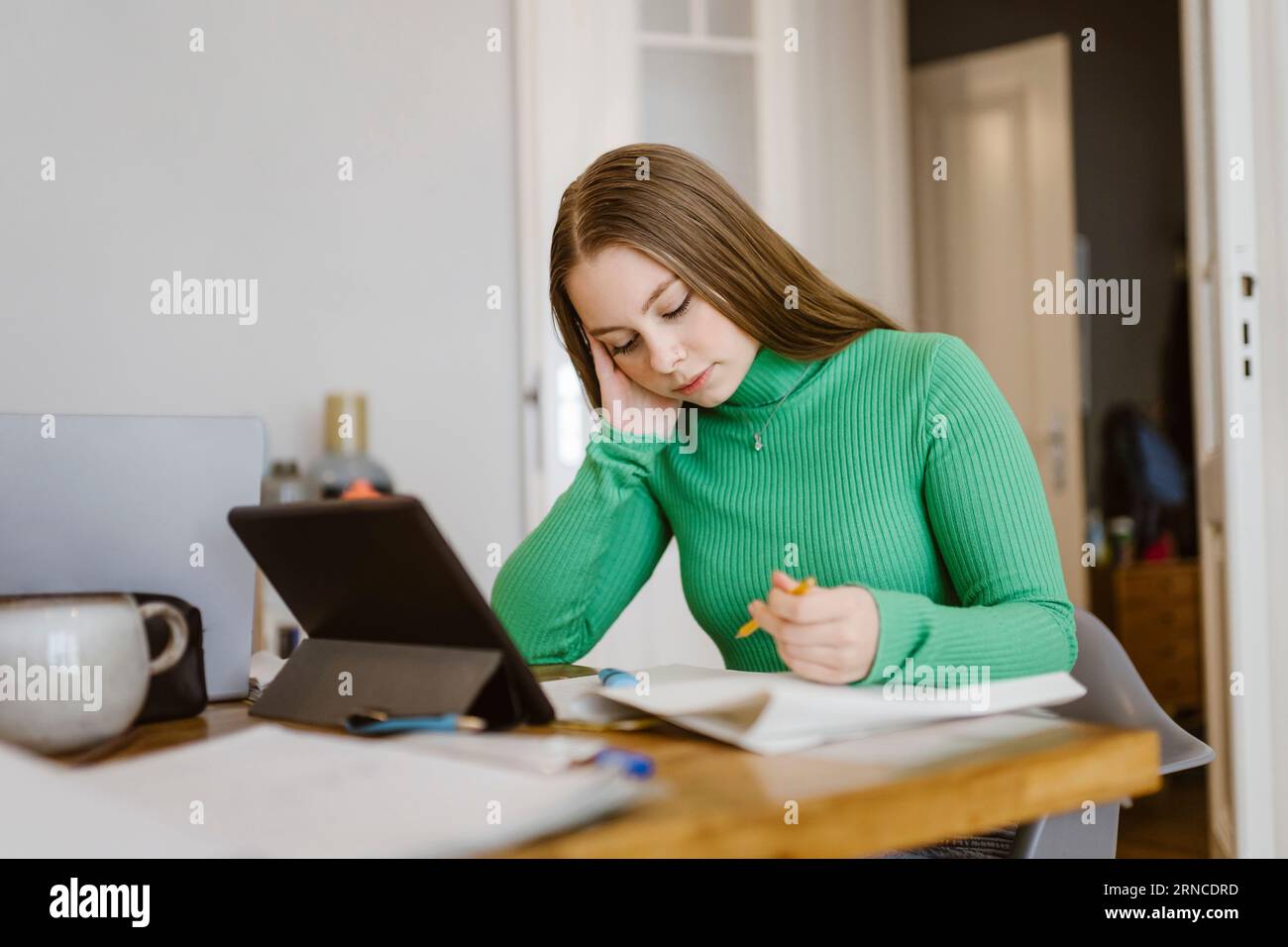 Bored young woman studying at table Stock Photo