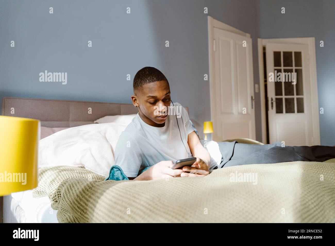 Young man using smart phone while lying on bed at home Stock Photo
