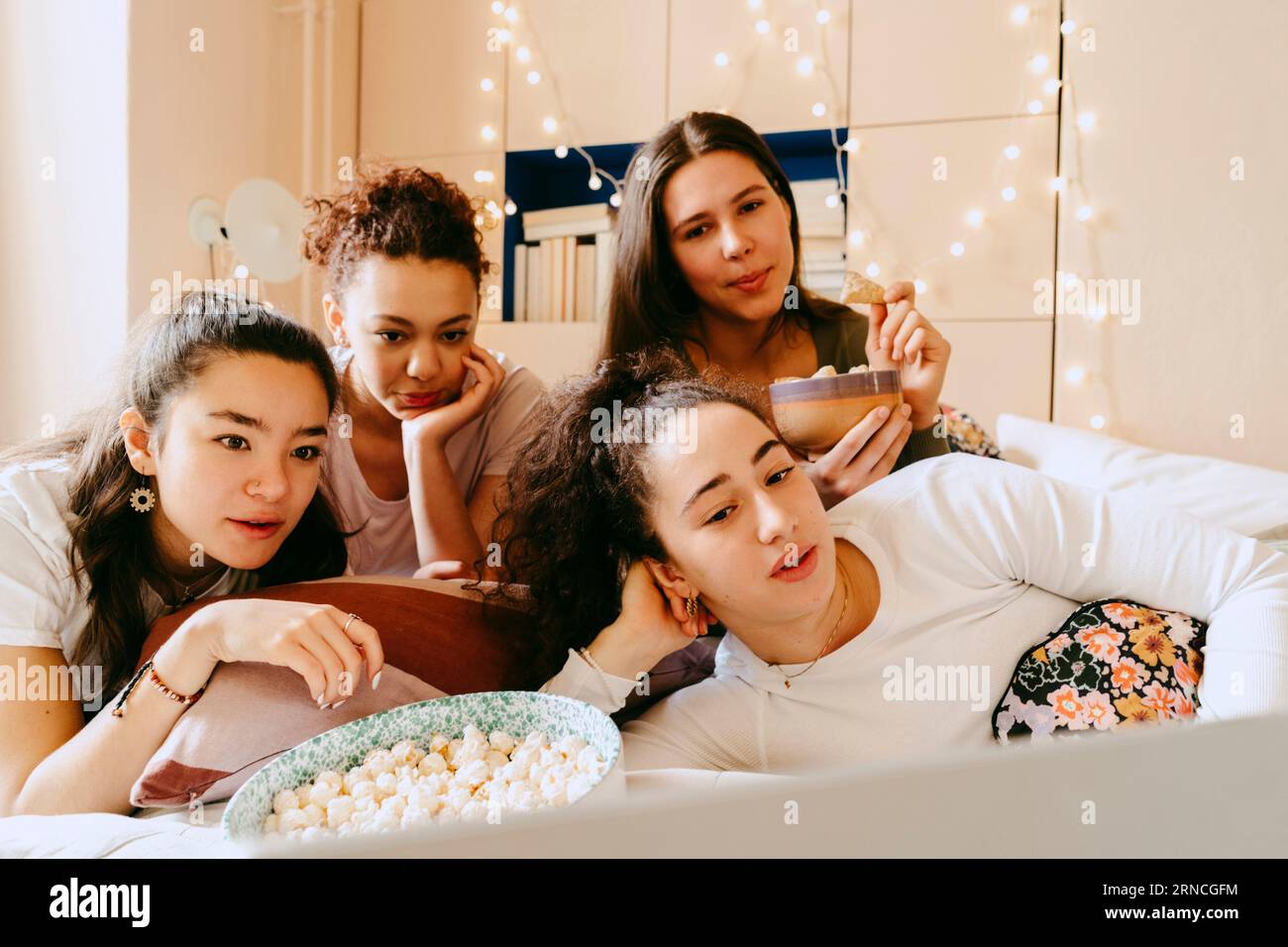 Multiracial female friends watching movie together on laptop at home Stock Photo