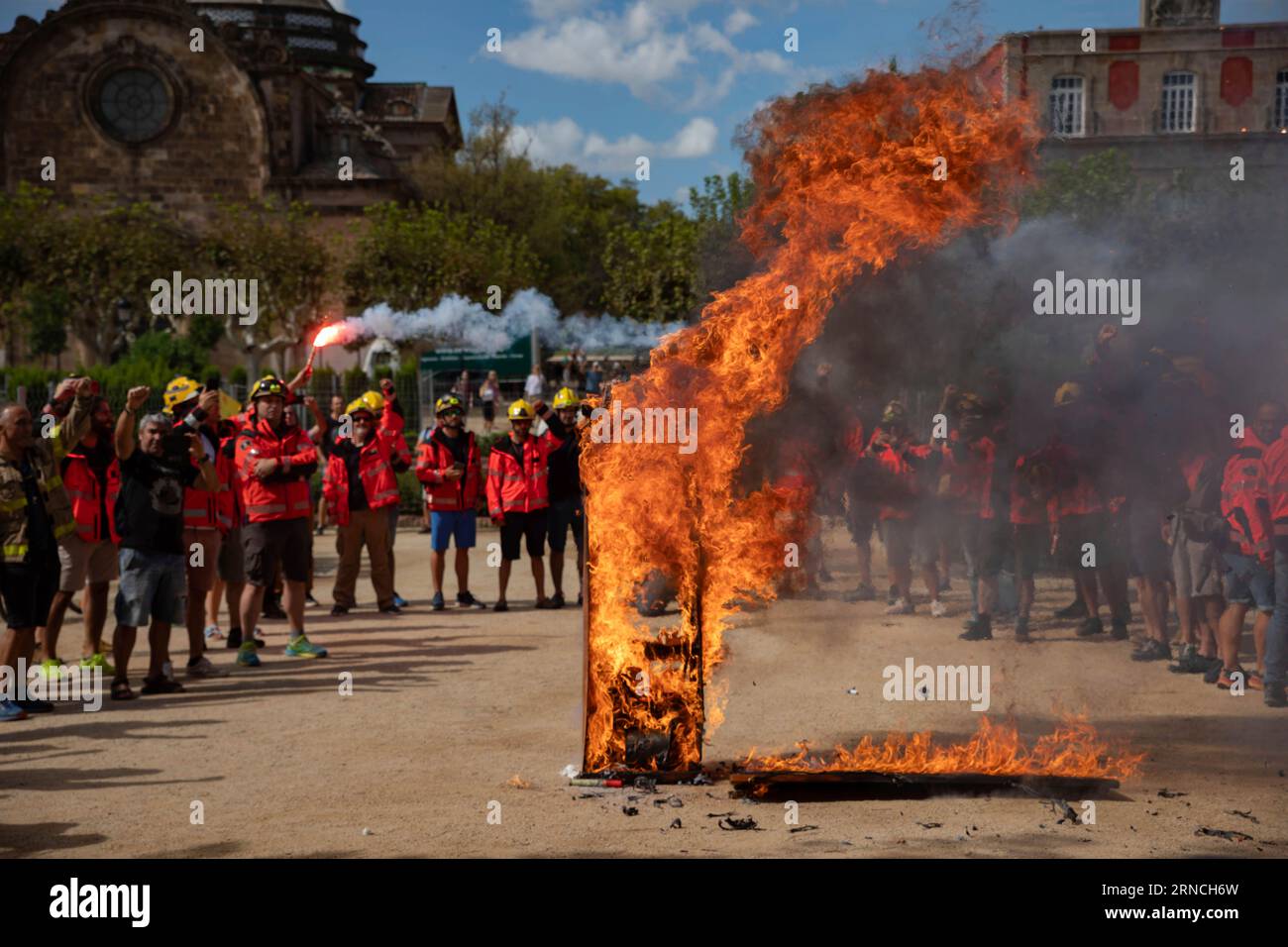 Several people next to a burning grave as a sign of protest during a  concentration of Bombers Voluntaris de Catalunya, in front of the Parlament  de Catalunya, on September 1, 2023, in
