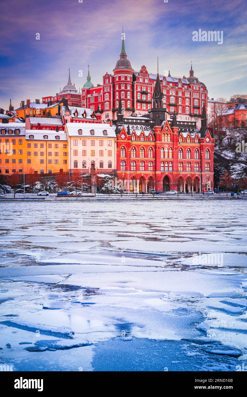 Stockholm, Sweden. Mariaberget and Sodermalm island in winter. Beautiful orange, violet and pink sky at sunset, reflected in frozen water of lake Mala Stock Photo