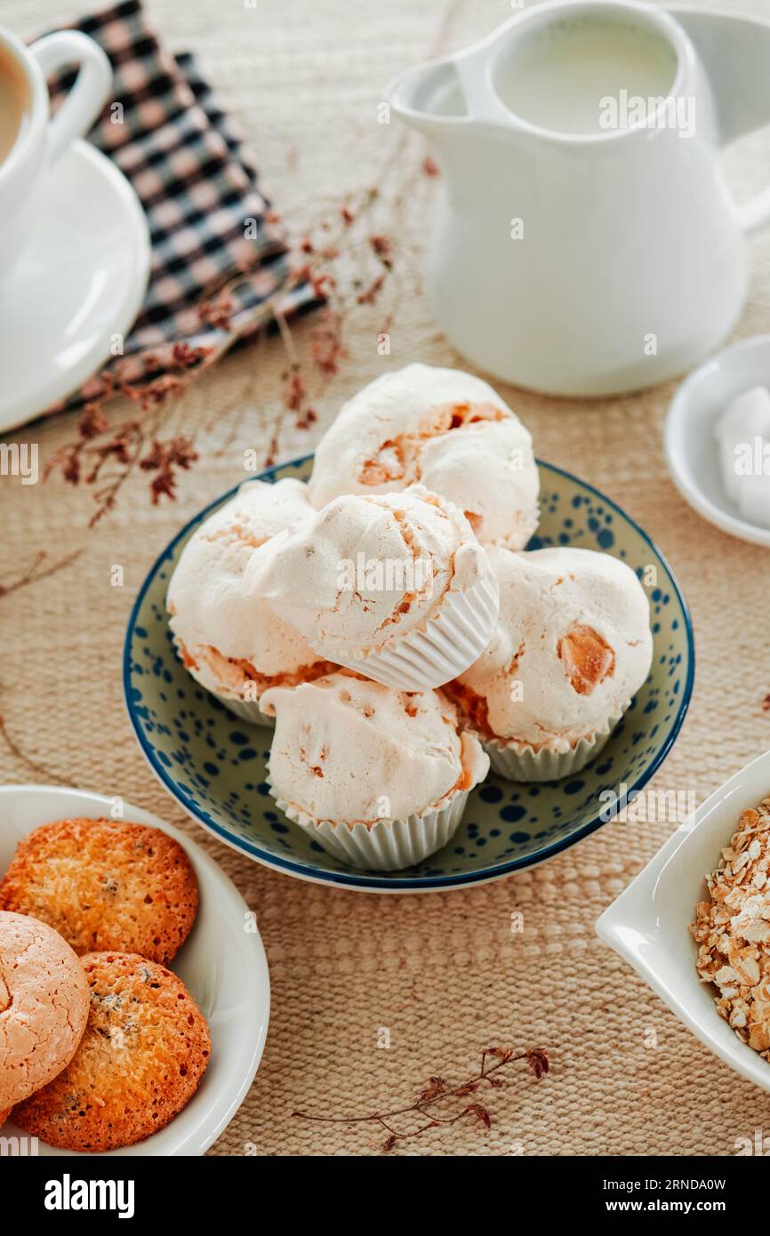 some spanish merengues almendrados, baked meringues with almonds, placed in a white ceramic bowl on a table set with a brown tablecloth Stock Photo